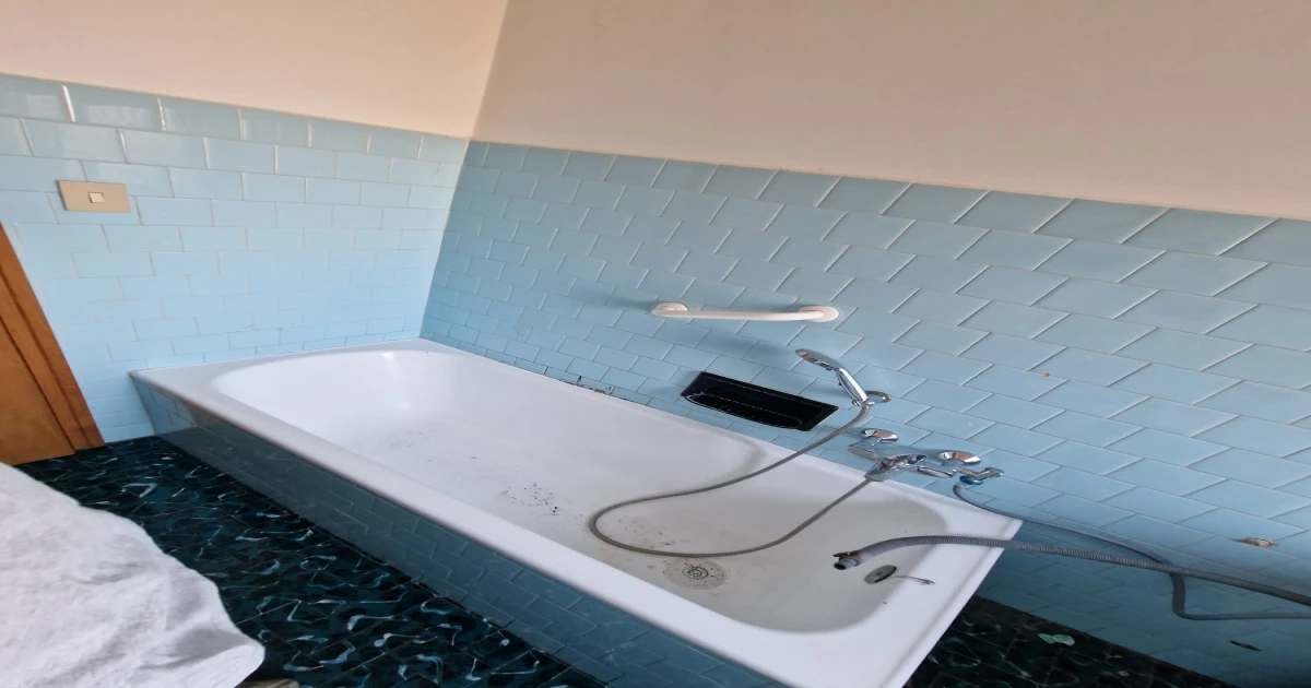 Bagno integro prima dell'intervento: vasca, piastrelle blu, pavimento a mosaico